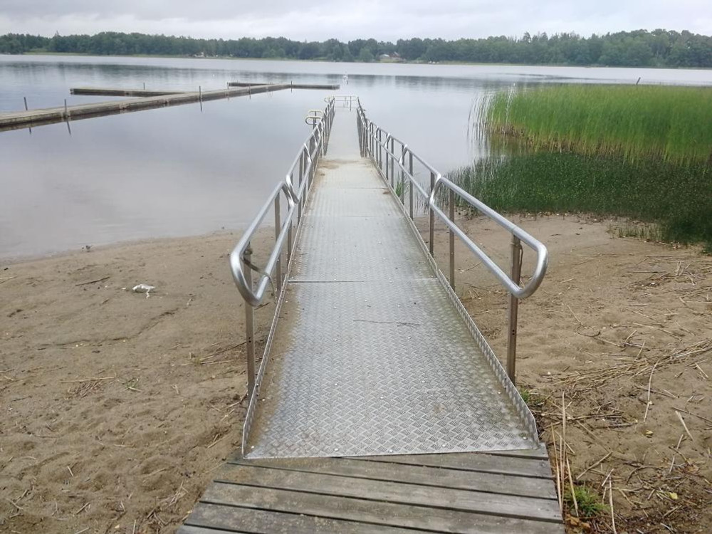 Badstrand. Tillgänglig brygga med ramp och sidoräcken.   