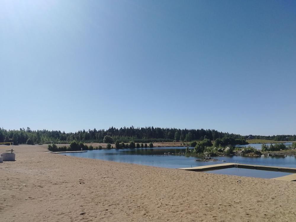 Ljus sandstrand. Brygga och klarblå himmel. 