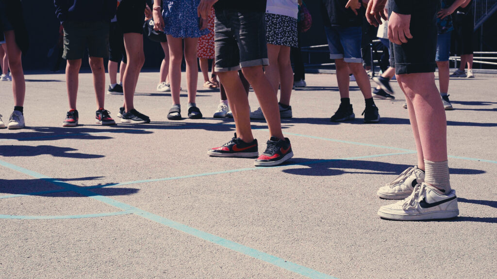 Beskuren bild på ben tillhörande ett tiotal barn på en skolgård.