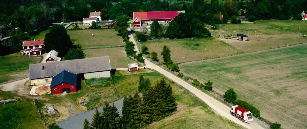 Flybild över landsbyggdsväg med röda hus och lador