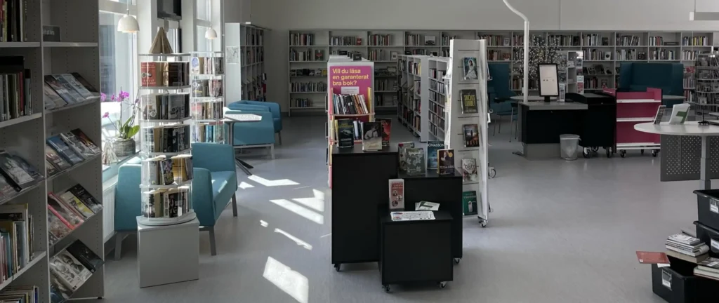 Biblioteket på Mohedaskolan med vita väggar och hyllor, möbler i turkos och svart och mängder med böcker.