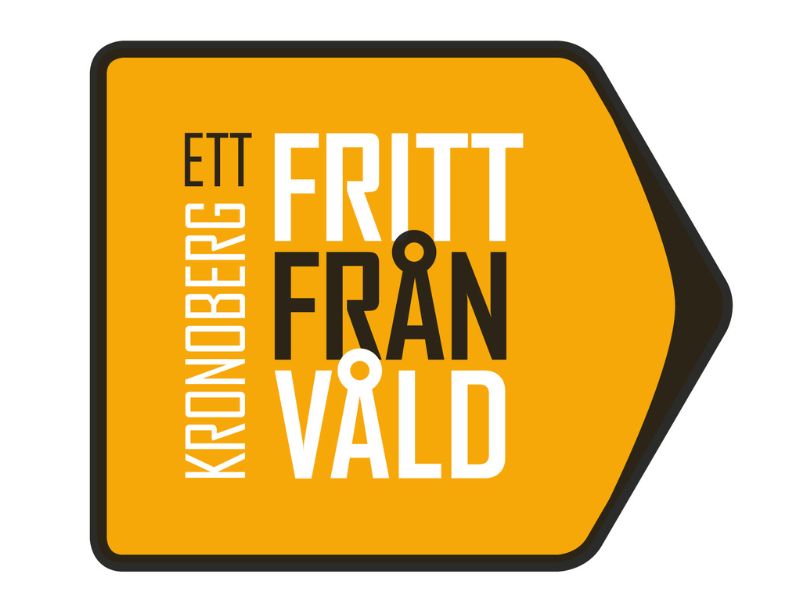 En pilformad logotyp i orange med svart kant. På pilen lyder budskapet "Ett Kronoberg fritt från våld".