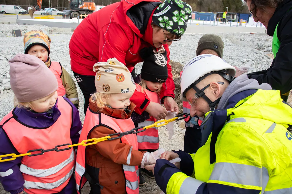 barn får hjälp av vuxna att sätta på sig plasthandskar
