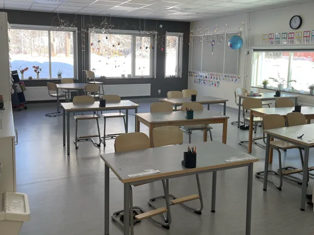 Ett tomt klassrum med bänkar och stolar.