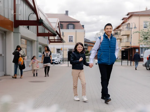 En man och en liten flicka går längs en gata.