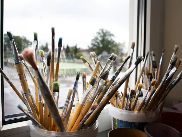 En massa målarpenslar ligger i en hink.