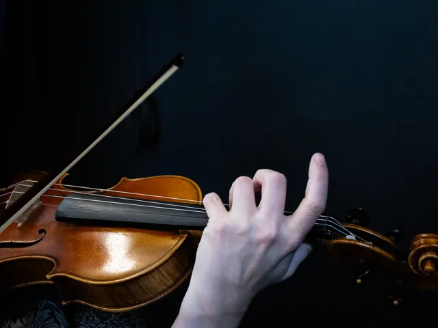 En person som spelar violin i ett mörkt rum.