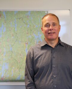 Porträttbild på man som  står framför en karta