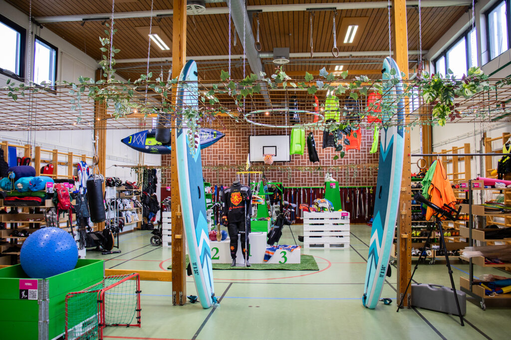 En sporthall inredd till en sportbutik med fritidsprylar överallt.