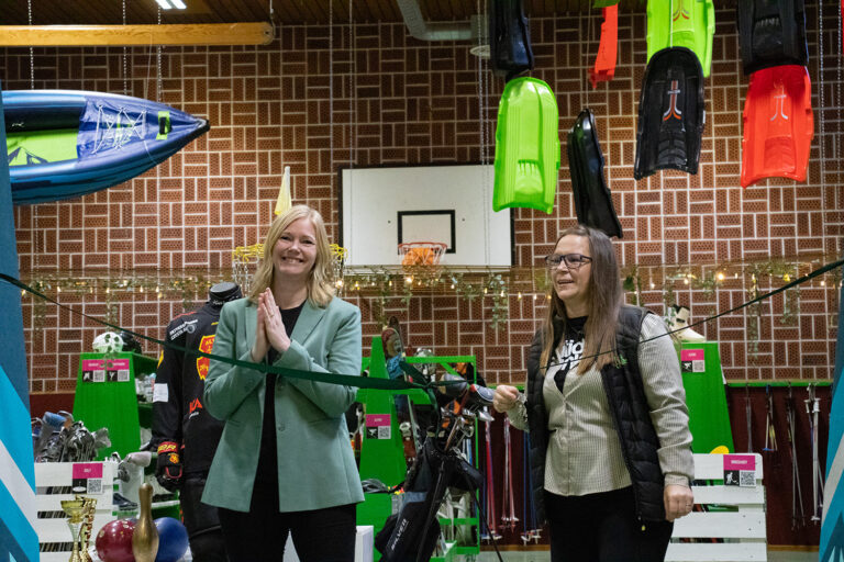 två kvinnor står bakom ett grönt band i en butik