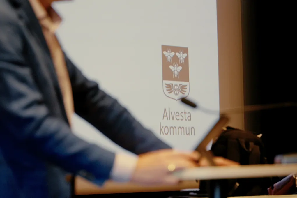 En man står på ett podium framför en projektorskärm.