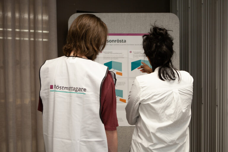 Två personer med västar på sig där det står röstmottagare.