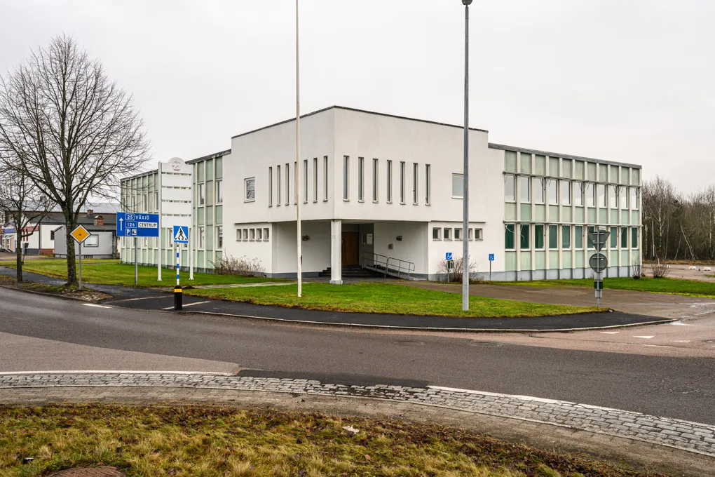 En vit byggnad med en krökt väg framför sig.