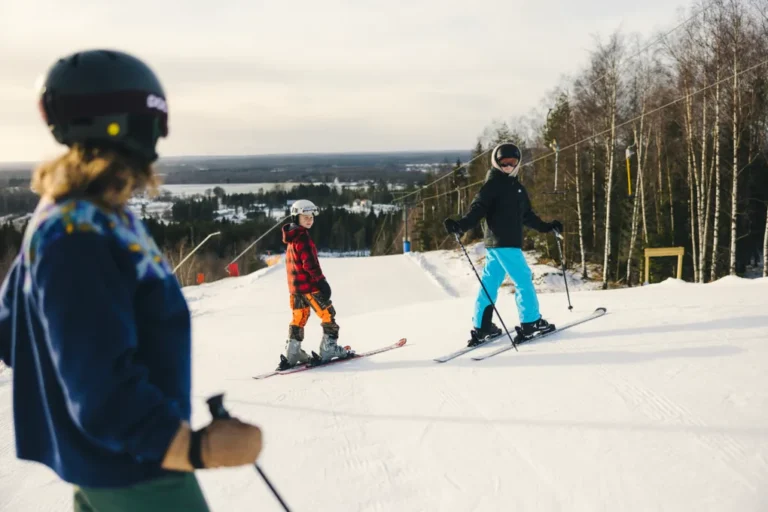 Tre skidåkare i mitten av skidbacke. Inga ansikten syns.