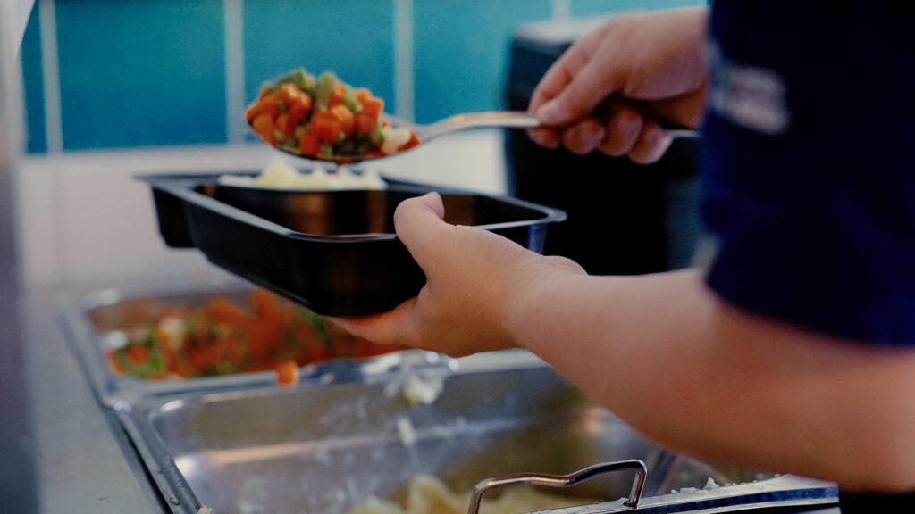 Person lägger upp mat i behållare.