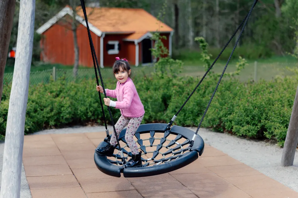 En liten flicka som svingar sig på en däckgunga.