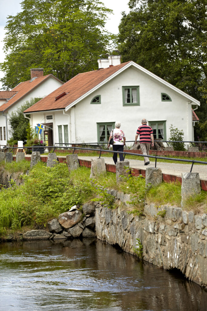 Några människor som går längs en gata intill en fors.