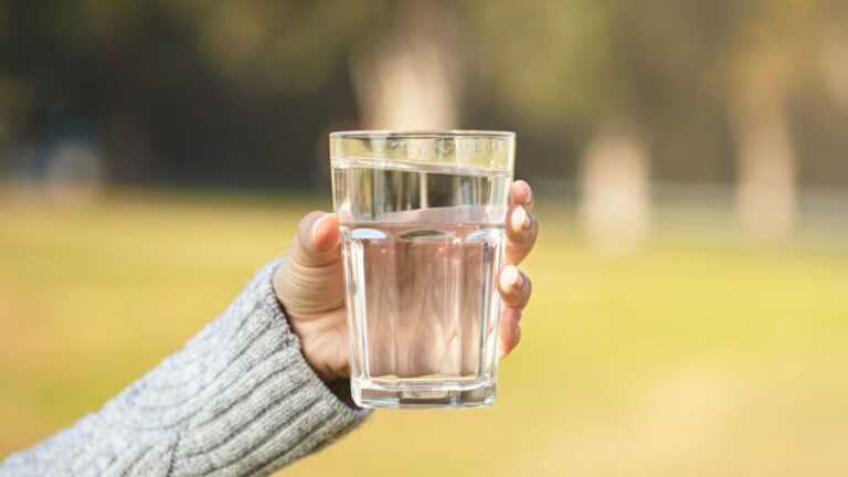 Hand som håller i fyllt vattenglas.