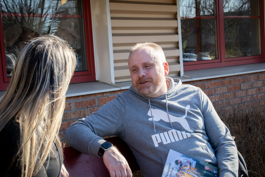 En man och en kvinna sitter utanför ett hus.