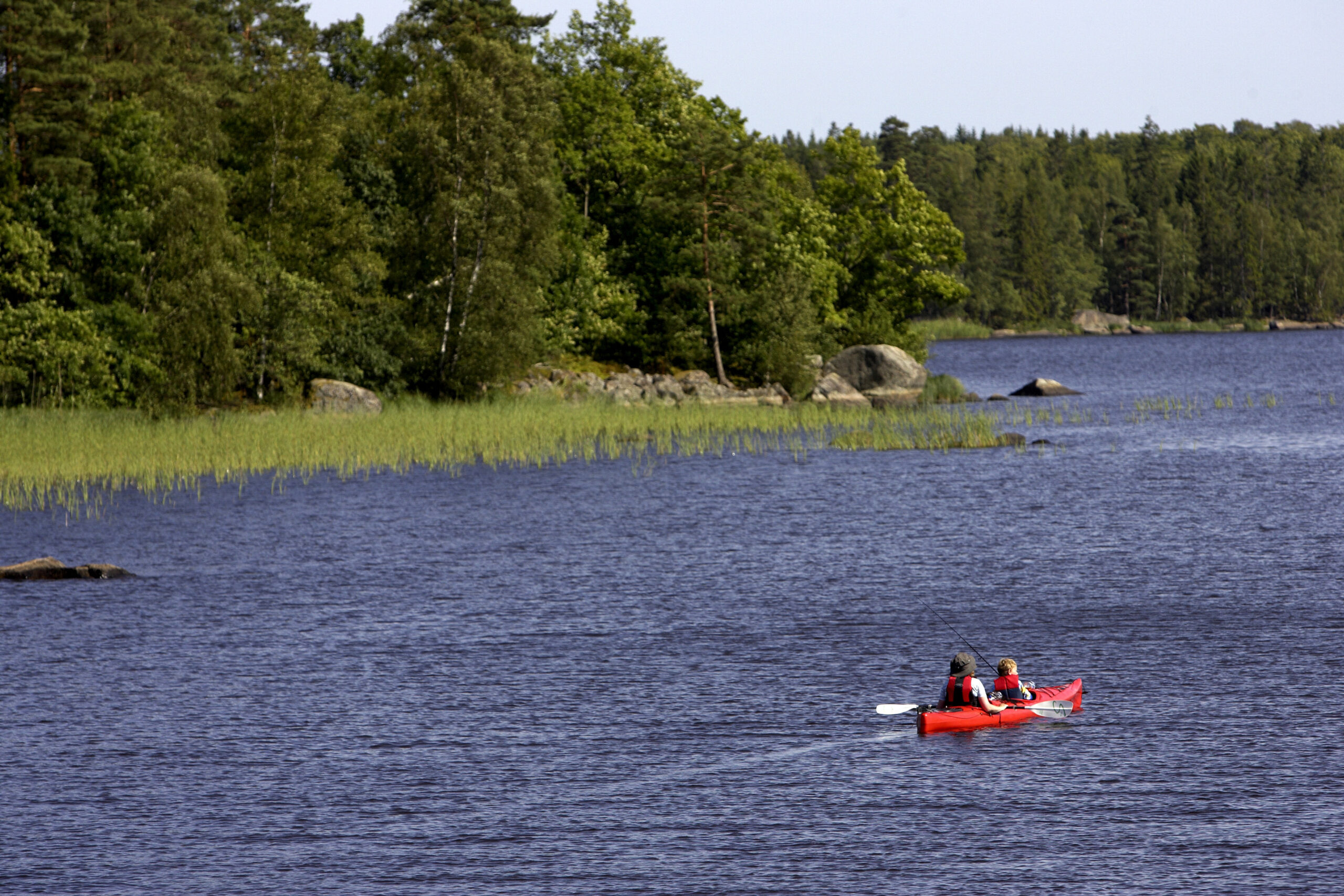 Två personer i en röd kanot på en sjö.