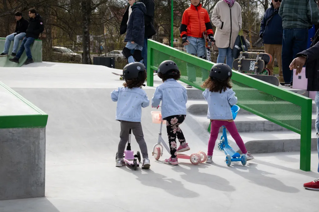 En grupp små barn som åker sparkcykel i en skatepark.