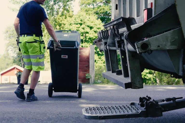 En man i varselkläder drar ett sopkärl.