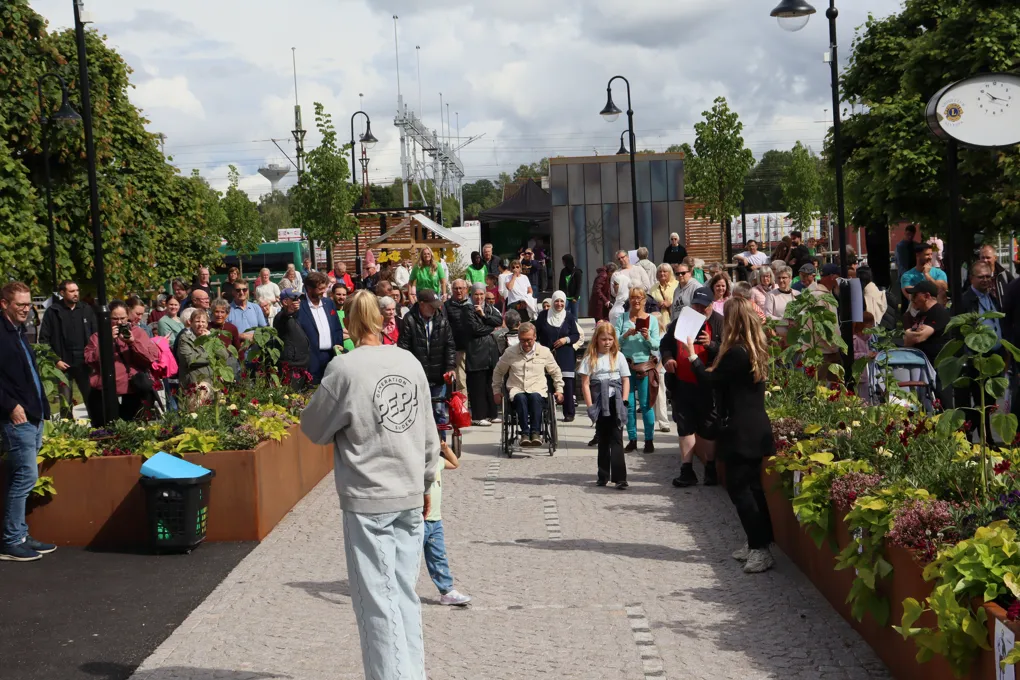 En folkmassa som går längs trottoaren.