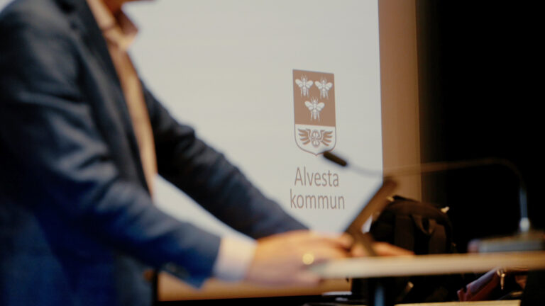 En man står vid ett podium framför en projektorskärm.
