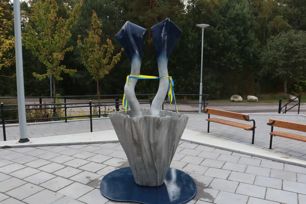 En skulptur i en park med bänkar i bakgrunden.