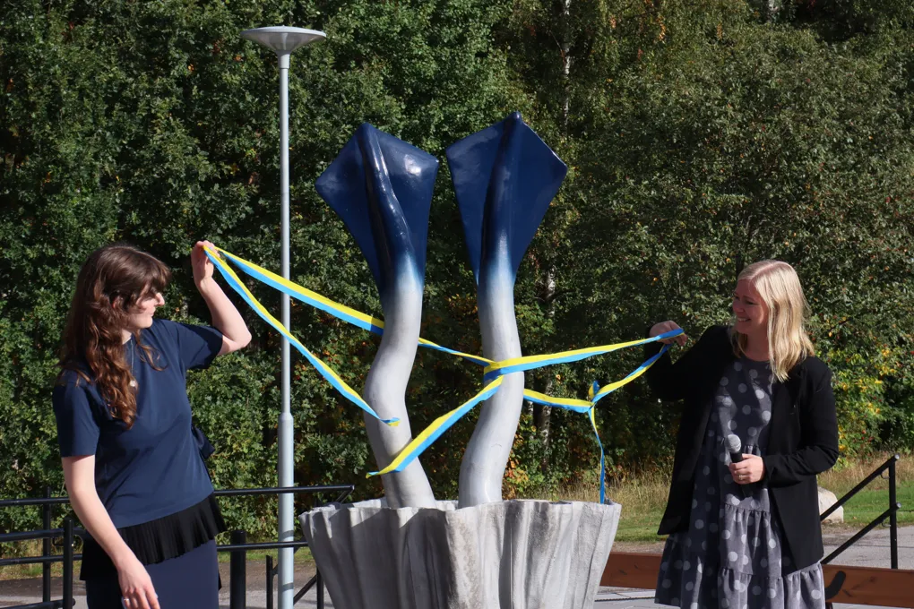 Några kvinnor som står bredvid en staty.