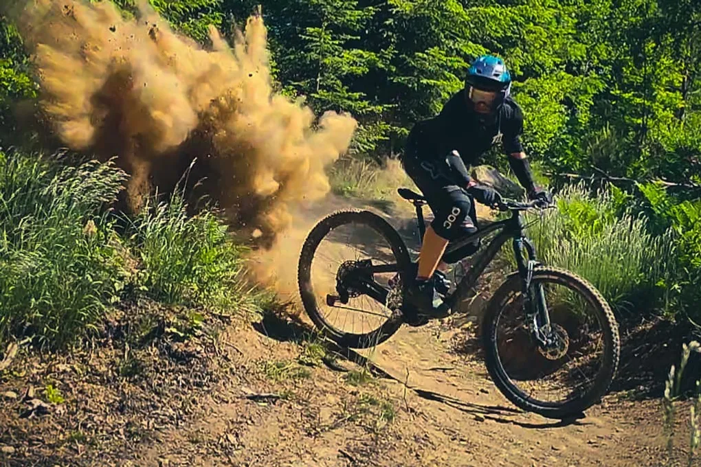 Cyklist på mountainbike. Ett moln av vägdamm syns bakom cykeln.